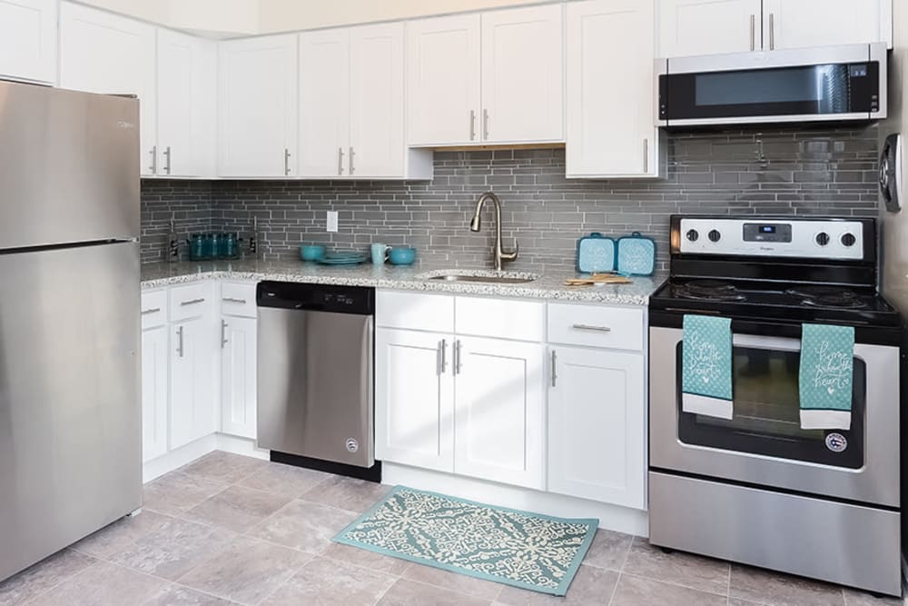 Kitchen with stainless-steel appliances and glass tile backsplash at Eatoncrest Apartment Homes in Eatontown, New Jersey