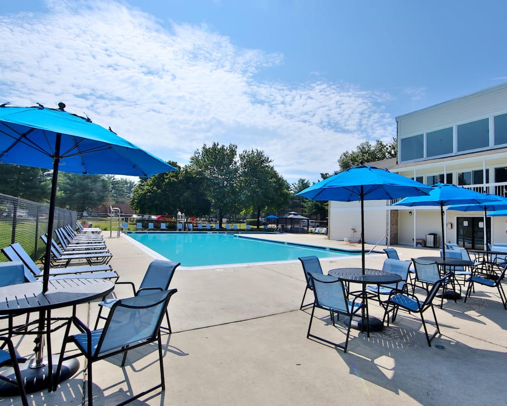Swimming pool and patio tables with umbrellas at Northampton Apartment Homes in Largo, Maryland