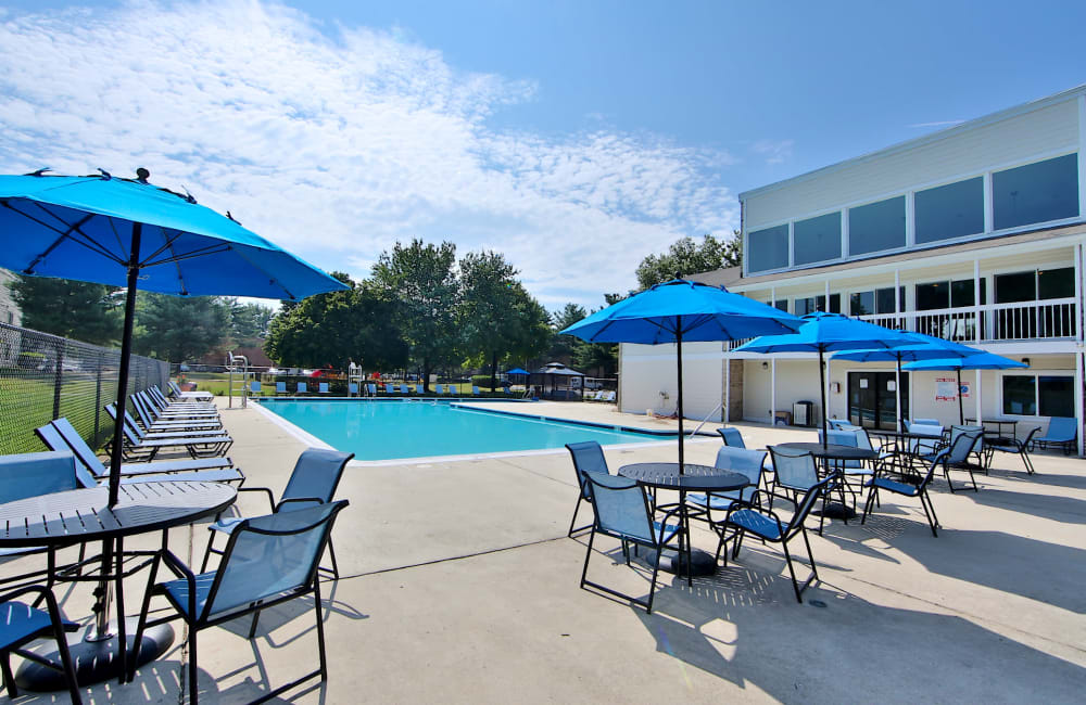 Swimming pool and patio tables with umbrellas at Northampton Apartment Homes in Largo, Maryland