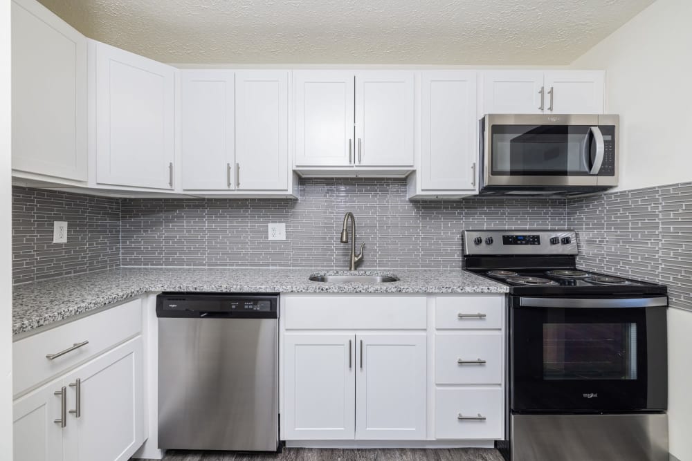 Kitchen with white cabinets, tile backsplash, and white appliances Westpointe Apartments in Pittsburgh, Pennsylvania