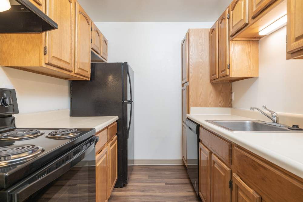 Galley style kitchen with wooden cabinetry at Squires Manor Apartment Homes in South Park, Pennsylvania