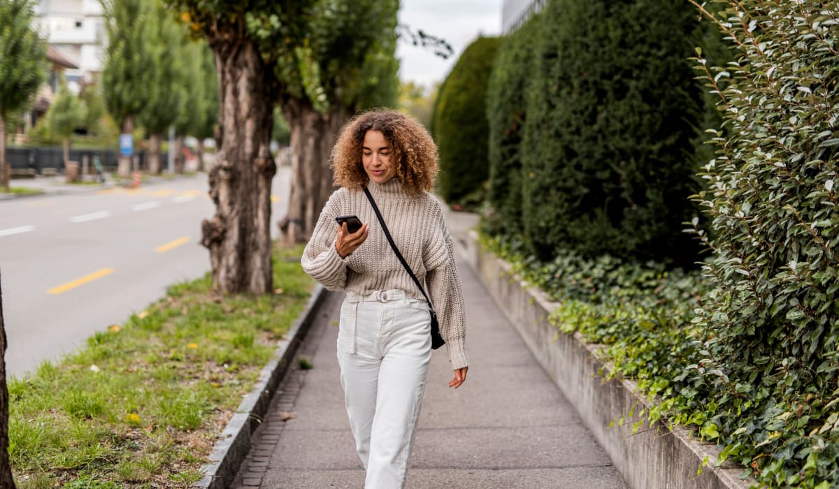 Girl on phone walking through city near Emerald Pointe Townhomes apartments in Harrisburg, Pennsylvania