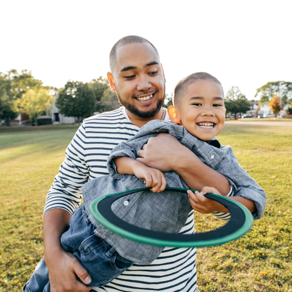 Resident playing with his son in a park near Woodcrest Apartment Homes in Dover, Delaware