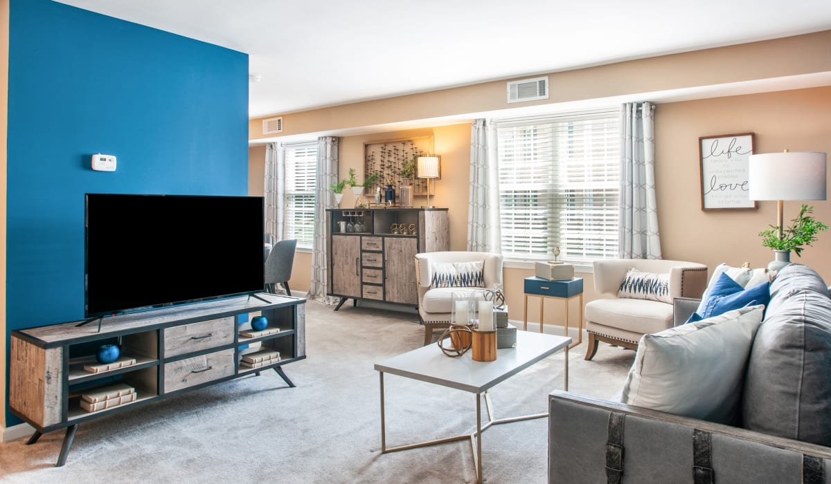 Well-lit living room with television, couch, and carpeted flooring at Montgomery Manor Apartments & Townhomes in Hatfield, Pennsylvania