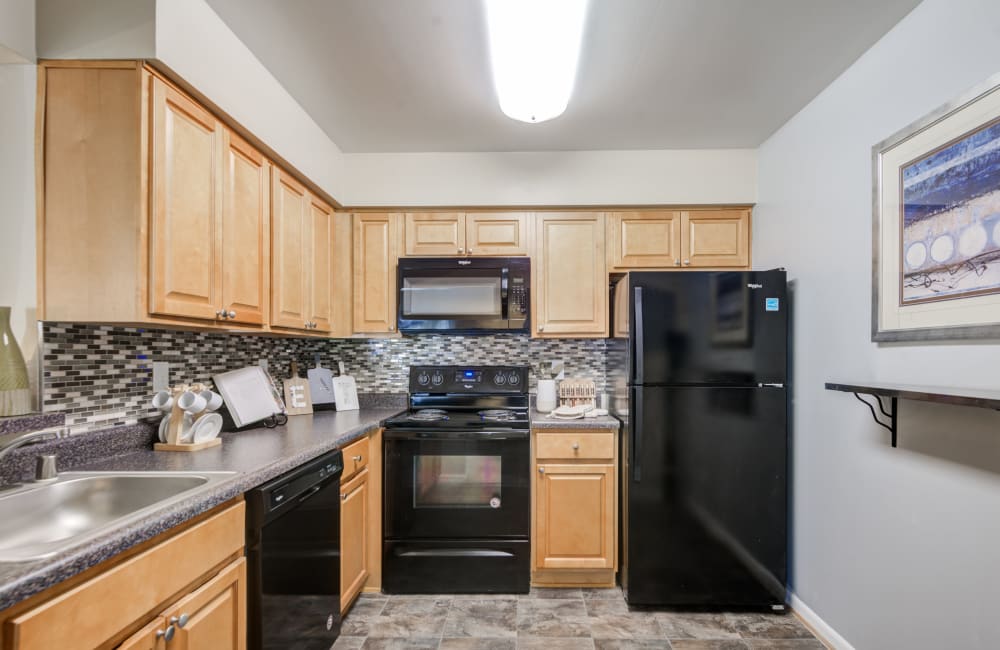 Kitchen with maple cabinets and black appliances at Northampton Apartment Homes in Largo, Maryland