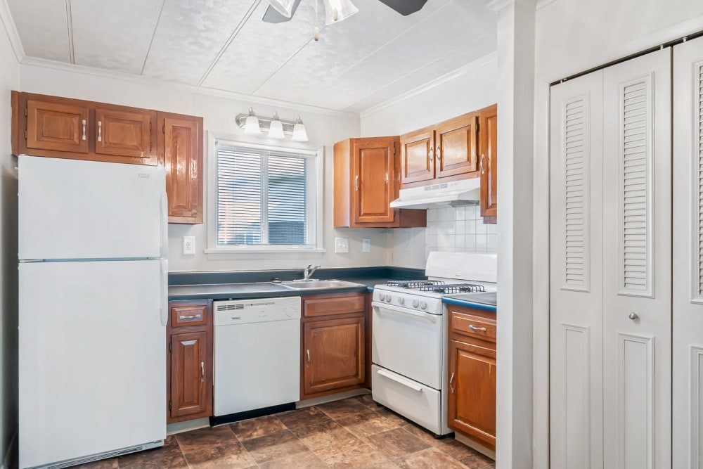Kitchen with Wooden Cabinetry and White Appliances at Oxford Manor Apartments & Townhomes in Mechanicsburg, Pennsylvania