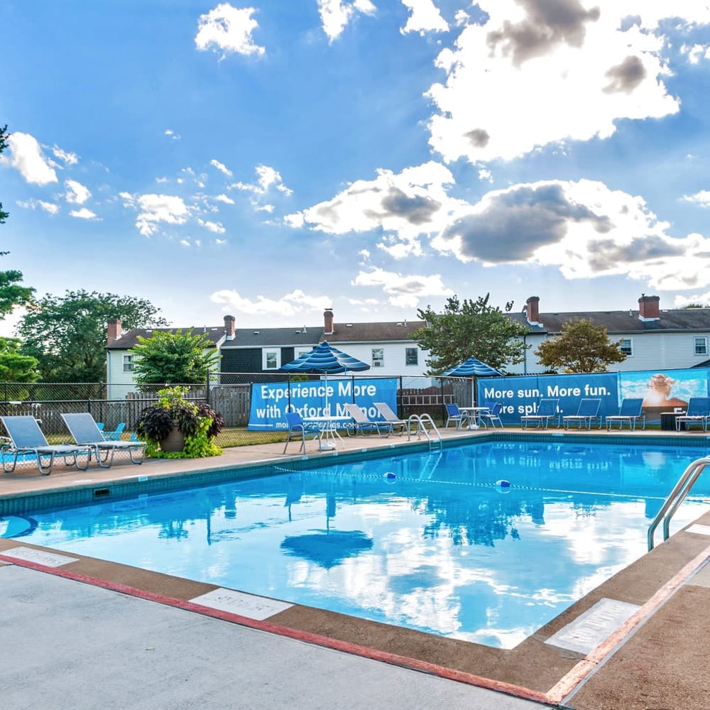Swimming pool surrounded by lounge chairs at Oxford Manor Apartments & Townhomes in Mechanicsburg, Pennsylvania