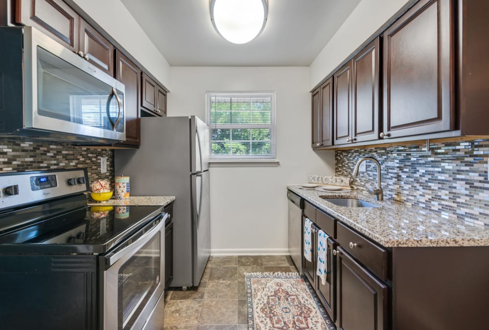 Galley-style kitchen with espresso cabinets and black appliances at Roberts Mill Apartments & Townhomes in Maple Shade, New Jersey