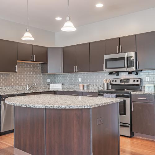 Open concept model kitchen with granite countertops and stainless steel appliances at Rochester Village Apartments at Park Place in Cranberry Township, Pennsylvania