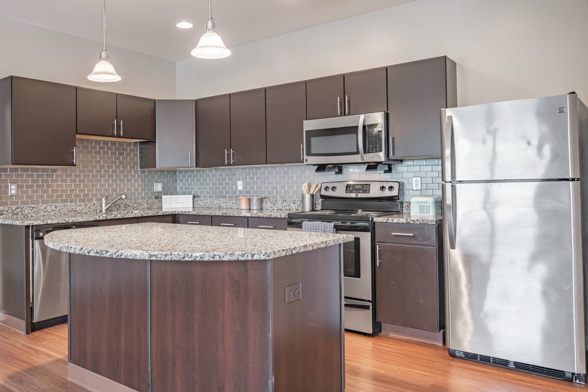 Kitchen with espresso cabinets, tile backsplash, granite countertops, and stainless steel appliances