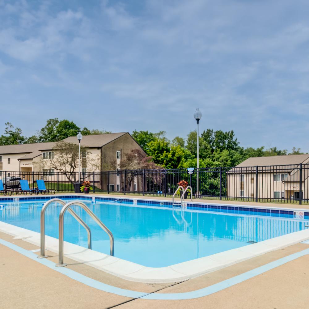 Swimming pool surrounded by lounge chairs at Squires Manor Apartment Homes in South Park, Pennsylvania