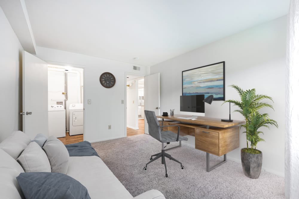 Bedroom with wall to wall carpeting and in-home laundry, staged as a home office at Steeplechase Apartments home in Camillus, New York
