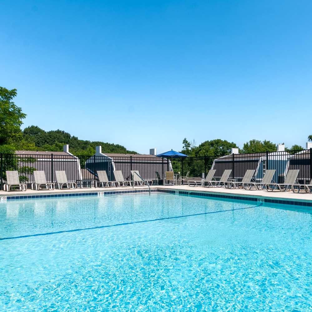 Swimming pool surrounded by lounge chairs at The Cascades Townhomes and Apartments in Pittsburgh, Pennsylvania