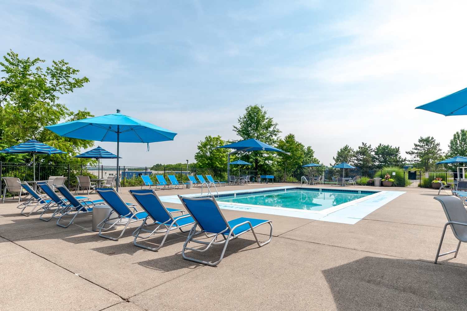 Resort-style pool with lounge chairs surrounded by lush woodlands at Westpointe Apartments, Pittsburgh, Pennsylvania